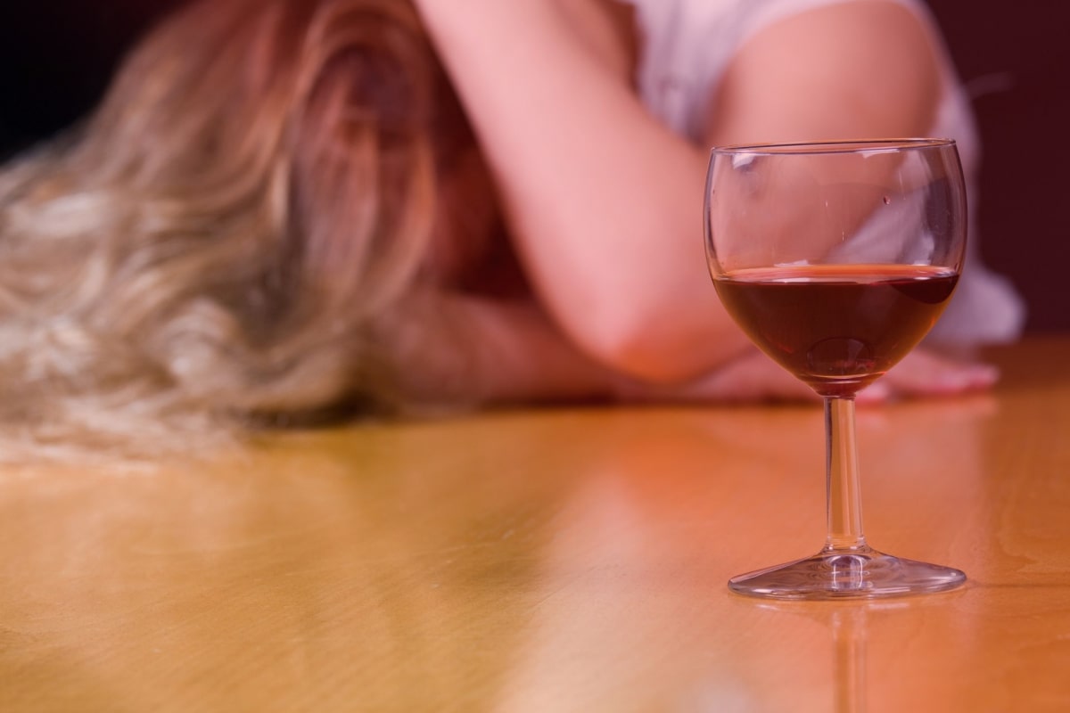 Девушка лежит рядом с бокалом вина